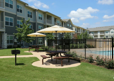 Outdoor seating area with benches and umbrellas at The Villages at Ben White