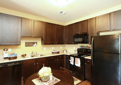 Kitchen at the Villages at Ben White senior apartments with brown cabinets and black appliances